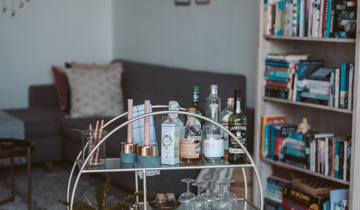 Styled home bar cart with bottles and glassware in a living room