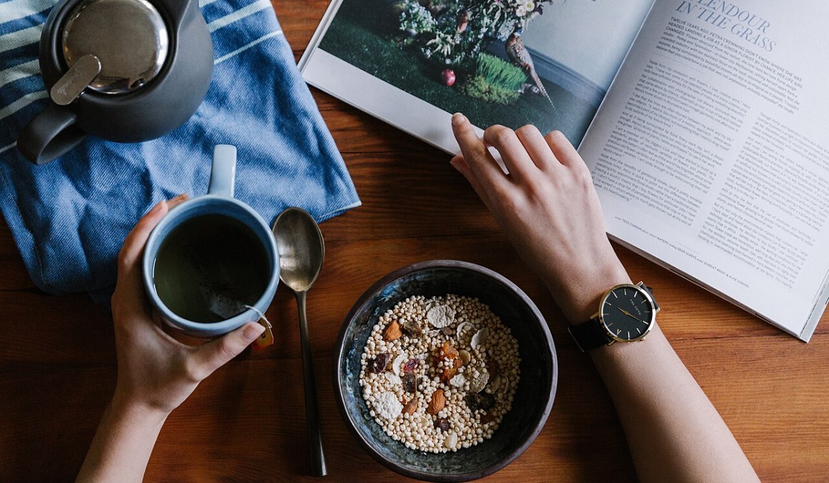 Overhead view of a relaxed breakfast with a mug of coffee, a bowl of oats and a magazine