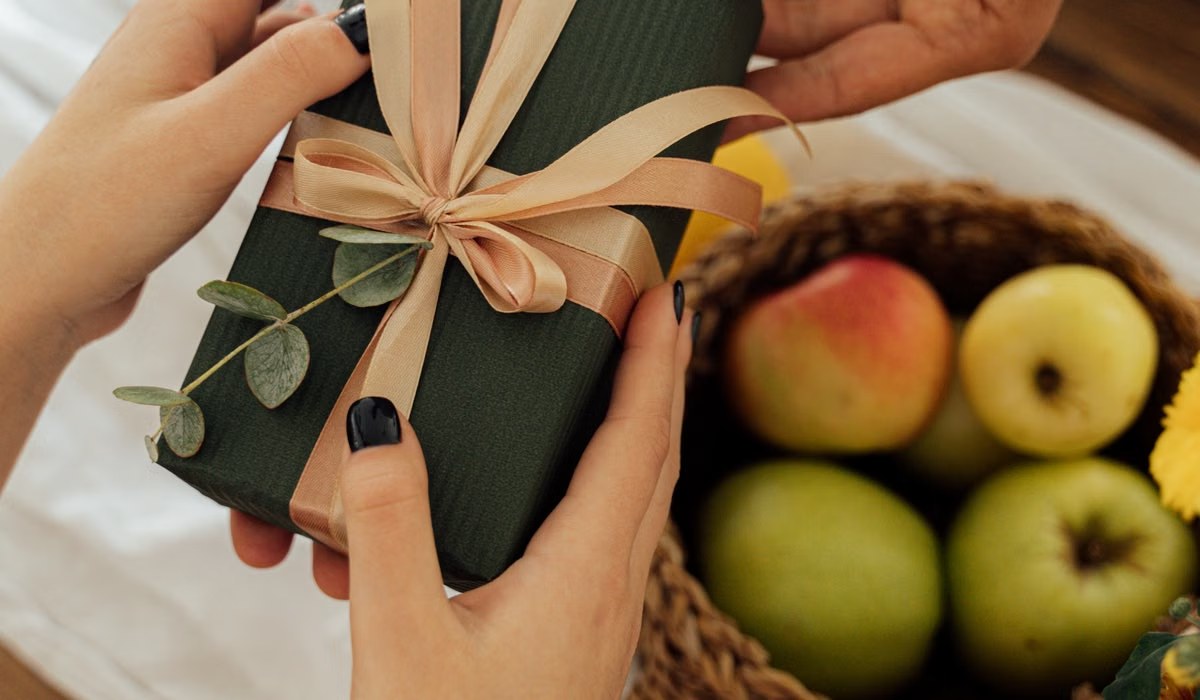 Hands exchanging a wrapped gift on a wooden table