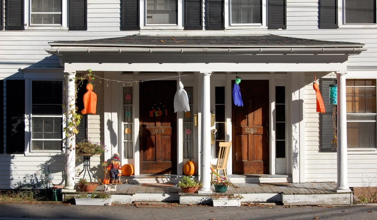 A cozy front porch layered with Halloween decorations at dusk